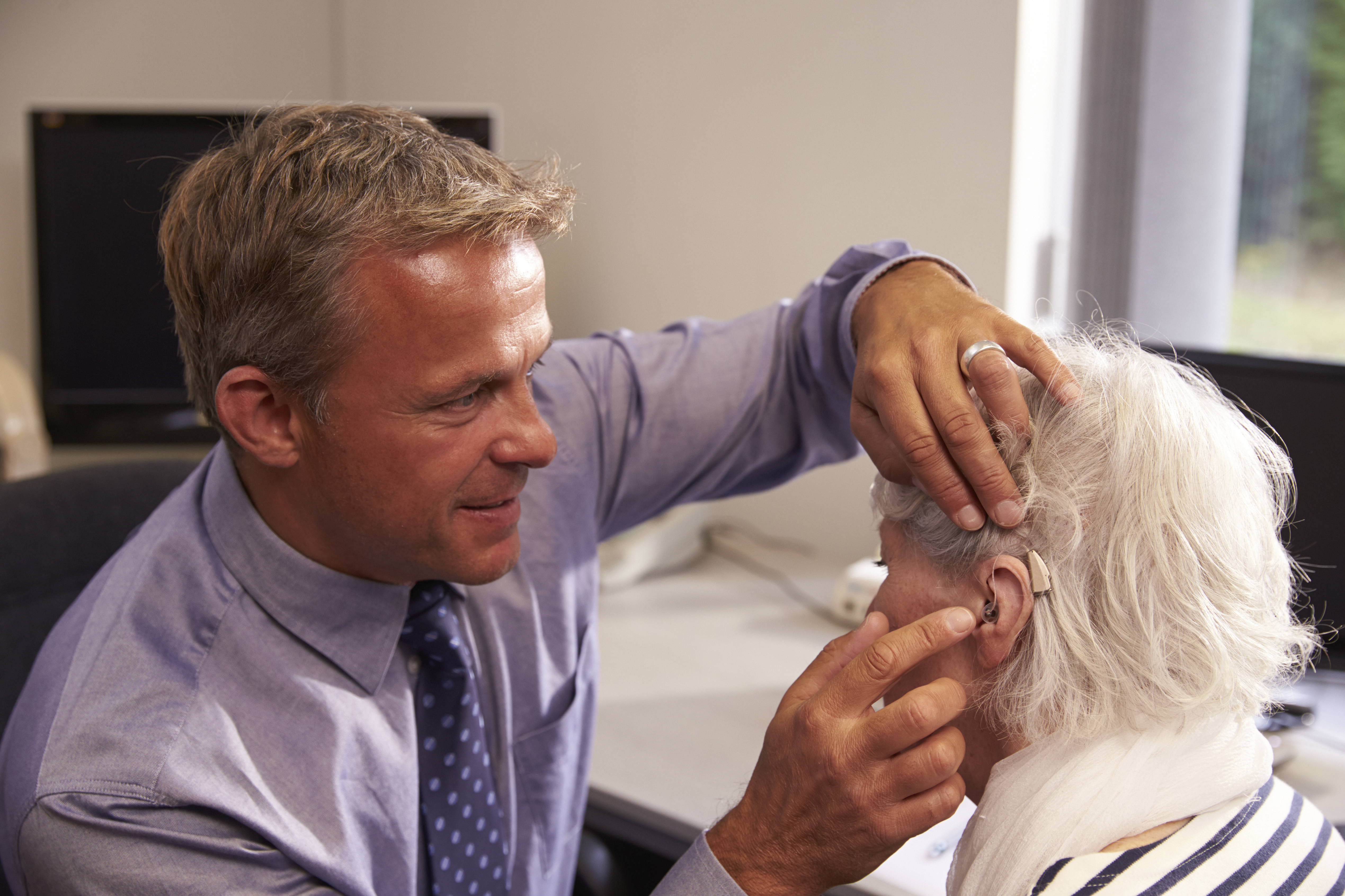 An audiologist fitting a new hearing aid